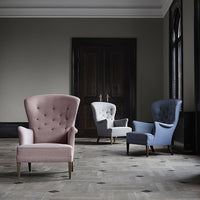 Stylish armchairs in pink, white, and blue upholstery featuring classic tufted designs in an elegant setting.