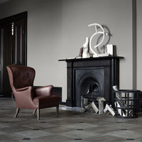 "Brown leather armchair in a minimalist gray room with geometric decor and a contrasting black fireplace."