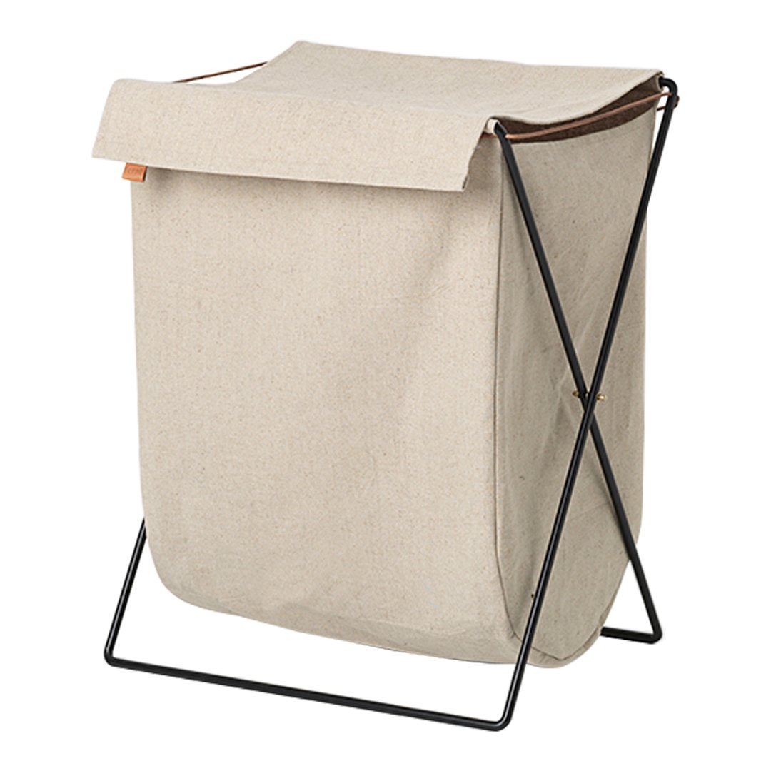 Beige fabric laundry basket with a black metal frame and a brown leather strap accent. Minimalist design.