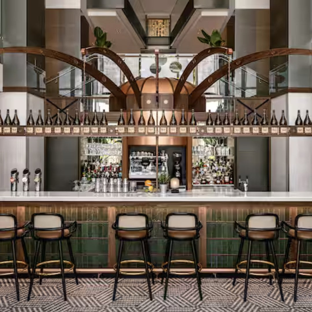 Modern bar with dark wood accents, green tiles, and geometric patterned flooring, featuring a sophisticated color palette.