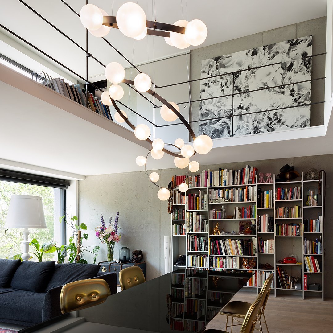 Modern chandelier with a sleek black frame and round white glass bulbs, set against a neutral-toned interior with bookshelves.
