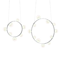 "Modern circular pendant lights in black metal with soft white globe bulbs, creating a minimalistic and elegant design."