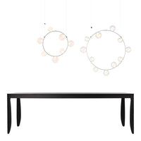 Black minimalist table with two circular pendant lights featuring pastel glass accents in soft hues.