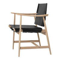 Nordic modern chair with a sleek black leather seat and natural wood frame, highlighting minimalist design.