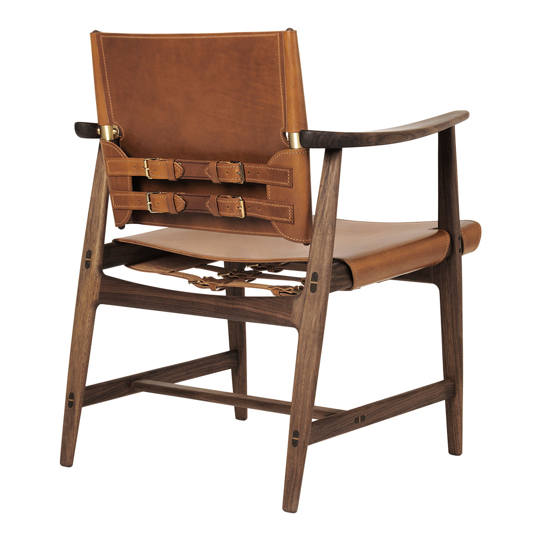 Brown leather chair with a sleek wooden frame and unique buckle detailing on the back. Modern, minimalist design.