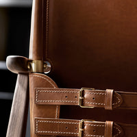 Close-up of rich brown leather with contrasting stitching and brass hardware accents. Elegant and sophisticated design.