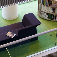 "Modern purple sofa on vibrant green carpet in a stylish indoor space."