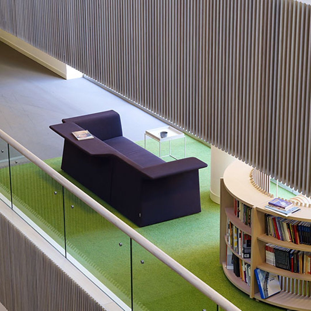Modern purple sofa on green carpet with sleek lines and minimalistic design, ideal for contemporary interiors.