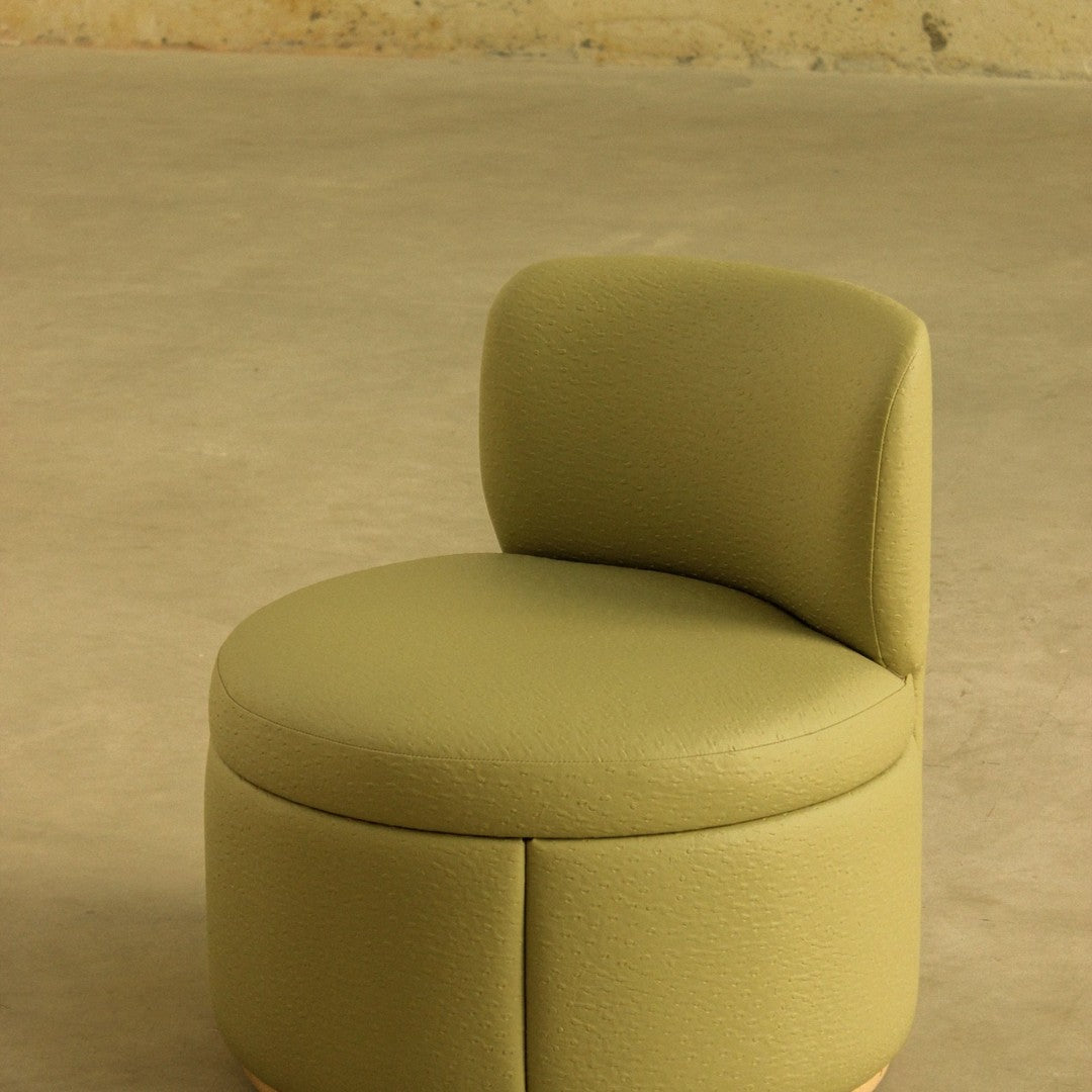 "Round olive green upholstered chair with smooth texture and minimalist design."