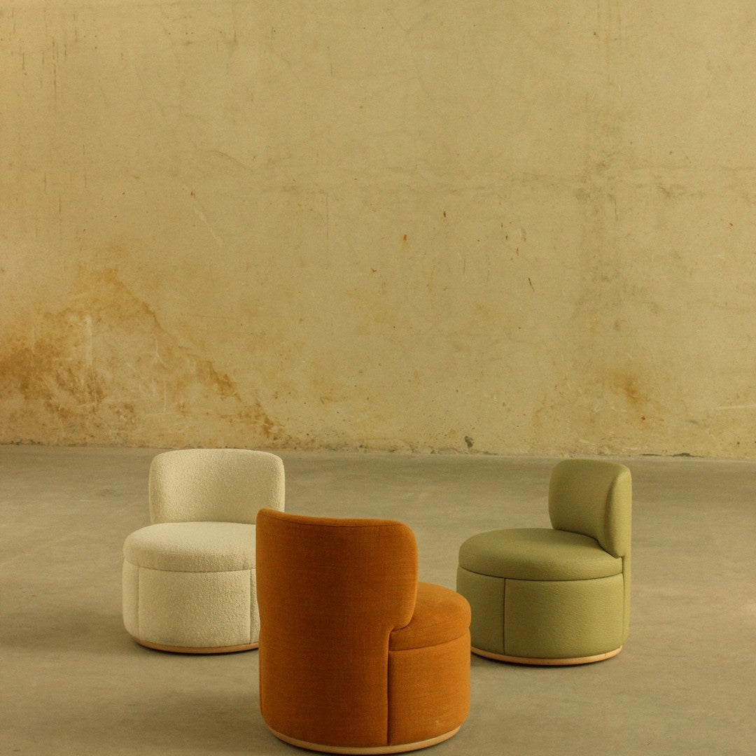 Three stylish accent chairs in orange, white, and green with smooth, modern upholstery against a neutral background.