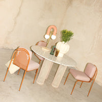 Light pink chairs and a speckled round table with a textured base, complemented by soft pastel accents.