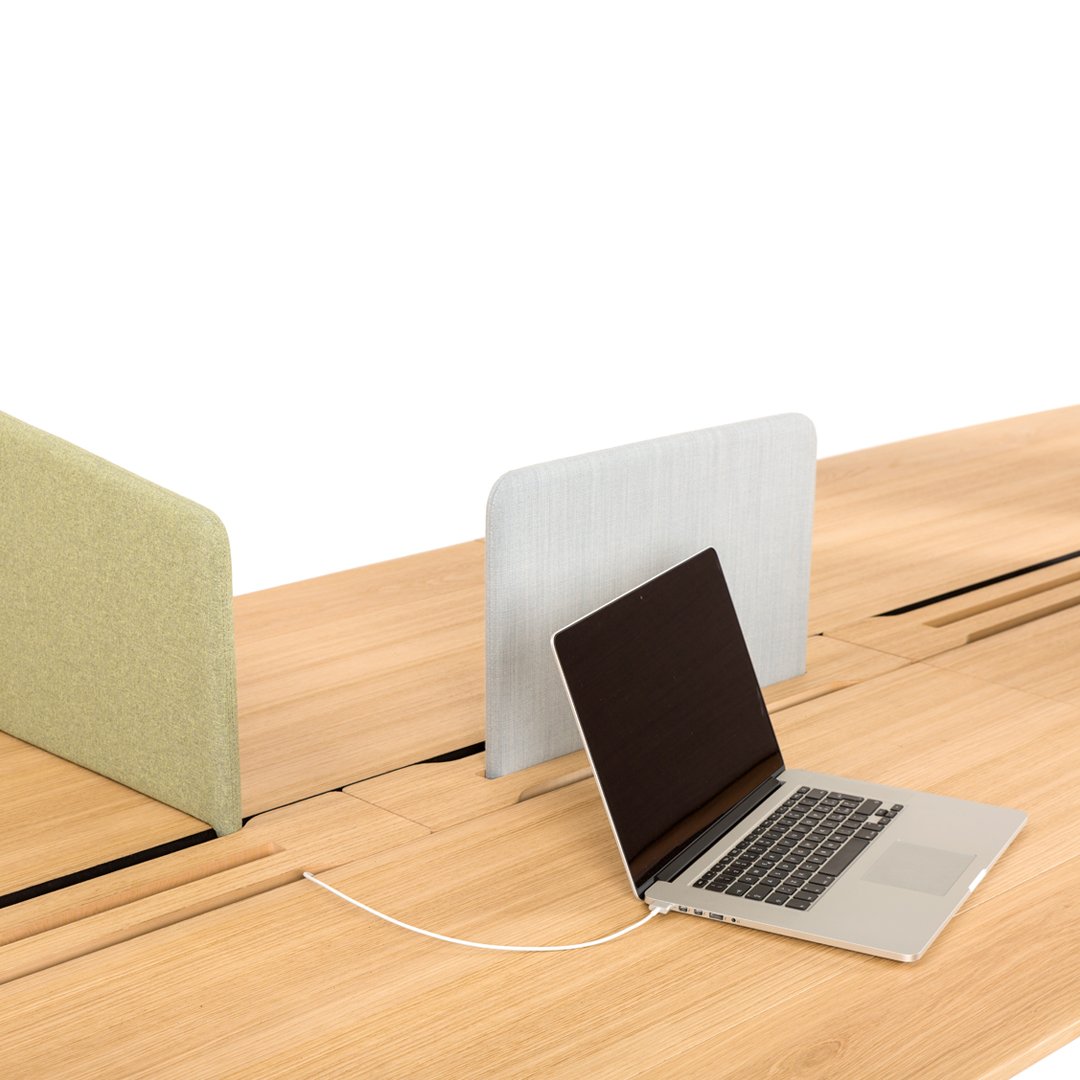 Light green and soft gray acoustic dividers on a wooden desk, complementing a sleek black laptop.