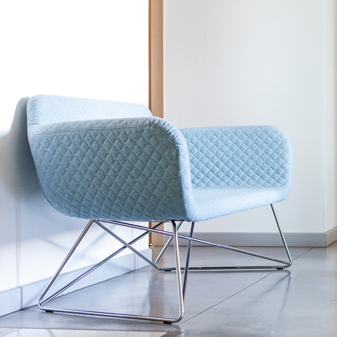 Light blue quilted fabric armchair with sleek chrome legs, perfect for modern decor.