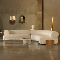 Cozy white boucle sectional sofa with natural wood accents and a light beige coffee table in a modern, minimalistic setting.