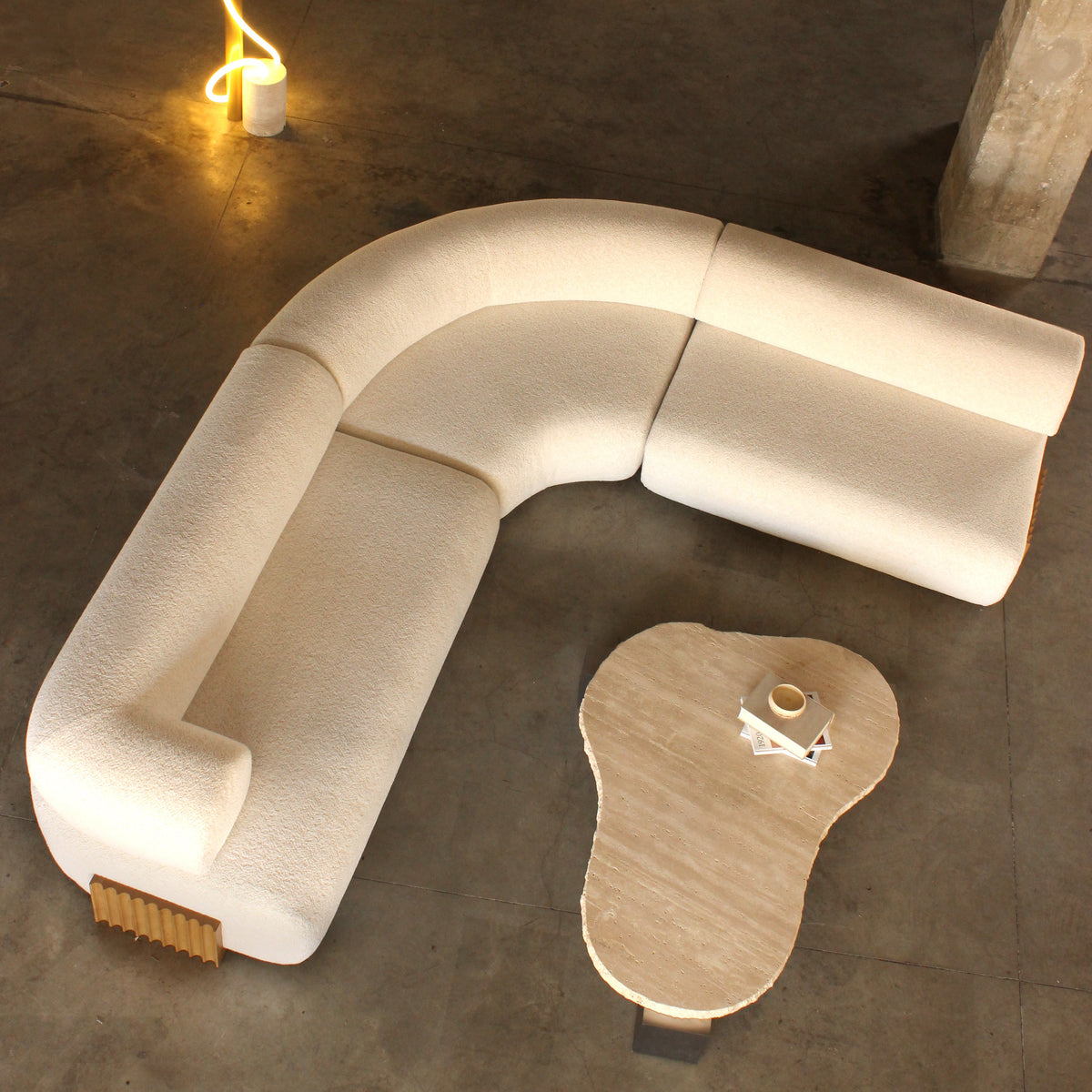 Curved cream boucle sofa with a textured finish, complemented by an organic-shaped light marble table.