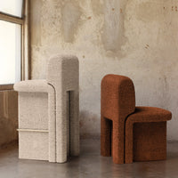Beige and rust-colored textured chairs with soft, rounded shapes against a rustic backdrop. Elegant and contemporary design.