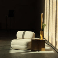 Light beige ribbed sofa with grey accents beside a gold side table and warm yellow vase. Soft, modern aesthetic.