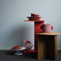 Colorful ceramics and bold orange shelving, featuring geometric and floral patterns on vases and plates.