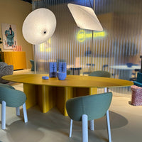 Modern dining set featuring a bright yellow oval table and soft green chairs in a stylish, patterned environment.