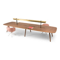 Elegant walnut desk with a smooth finish, featuring a gold metal accent and paired with soft pink chairs.