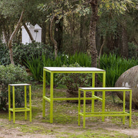 Bright green metal furniture set with sleek white tabletop, featuring two side tables and a taller table in a natural setting.