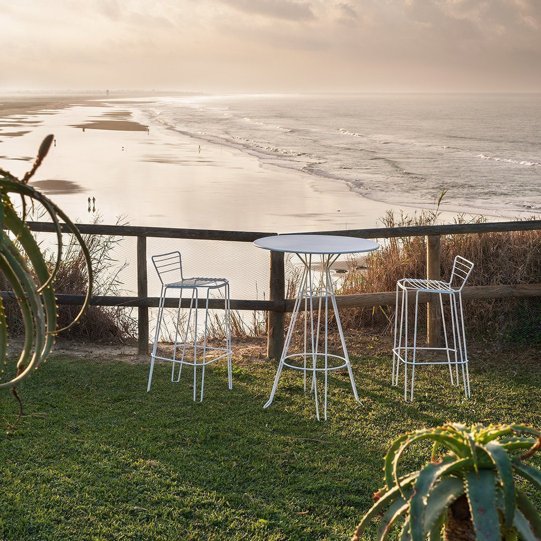 White metal outdoor bar set against a scenic beach backdrop, featuring sleek lines and modern design.