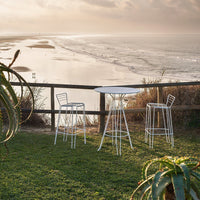 White metal outdoor bar set against a scenic beach backdrop, featuring sleek lines and modern design.