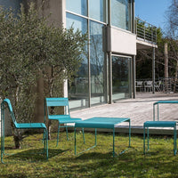 Teal outdoor furniture set with sleek lines, featuring a minimalist design against a natural green backdrop.