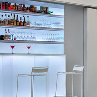 Sleek white bar with glowing blue underlighting, complemented by a minimalist design and clear glassware.
