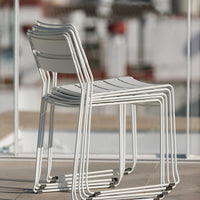 Stackable white chairs with sleek lines and minimalistic design, perfect for modern outdoor settings.