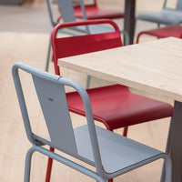 "Modern chairs featuring red and light blue colors with sleek metal frames, set around a wooden table."