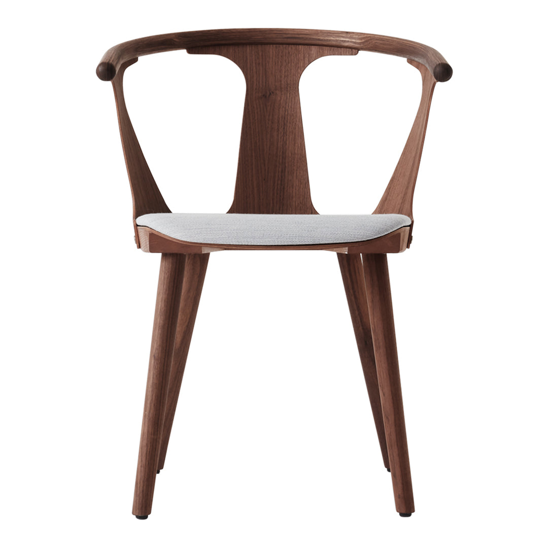 Brown wooden chair with a smooth white seat and curved backrest, featuring a modern, minimalist design.