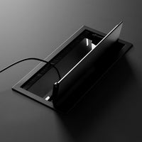 Sleek black charging station with smooth glass and a minimalist design, featuring subtle lines and reflections.