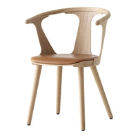 Light wood chair with natural finish and tan leather seat, featuring a sleek, minimalist design and curved armrests.