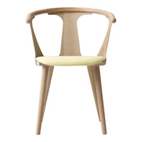 Light wooden chair with a curved backrest and a soft yellow cushion, featuring a minimalist design.