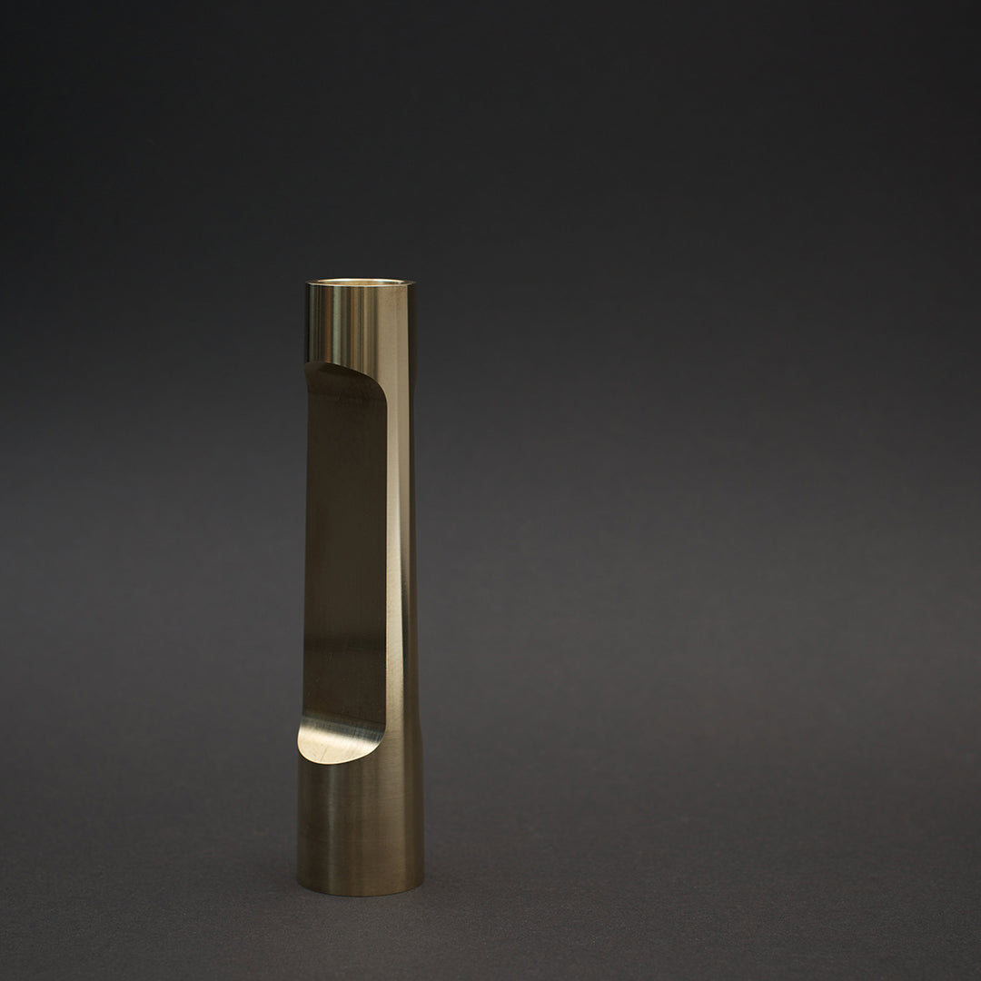 Gold metal vase with a sleek, minimalist design and polished finish against a dark background.