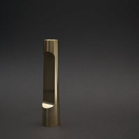 Gold metal vase with a sleek, minimalist design and polished finish against a dark background.