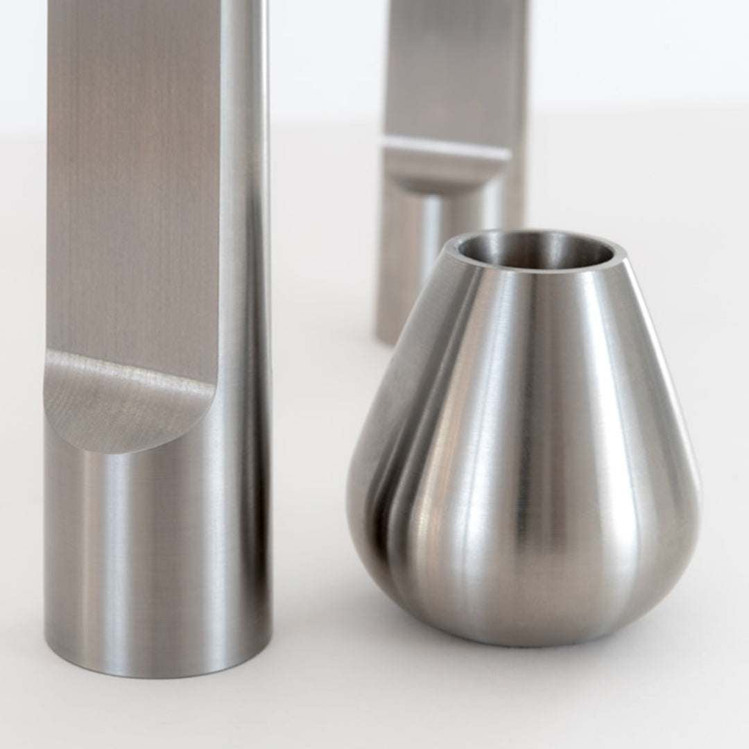 "Shiny silver metal decor pieces with smooth and textured surfaces, featuring modern geometric designs."