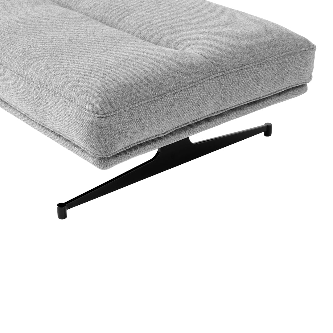 Gray upholstered cushion with a smooth texture and a sleek black metal base, perfect for modern decor.