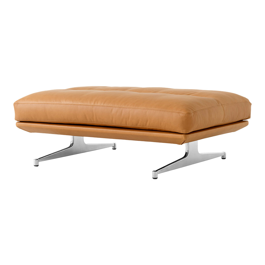 Tan leather ottoman with tufted detailing and sleek chrome legs, offering a modern, minimalist aesthetic.