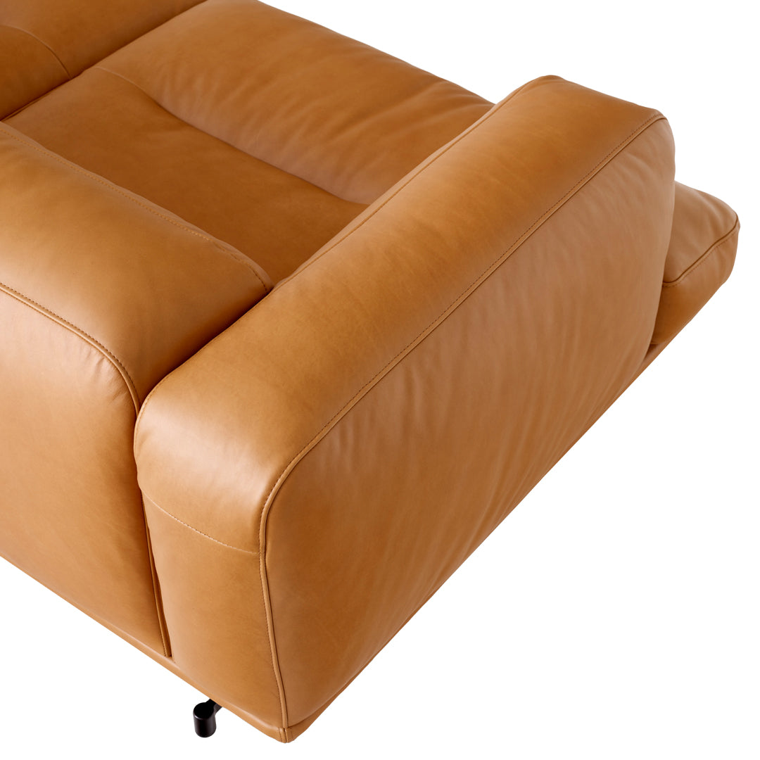 Tan leather sofa with smooth texture and minimalistic design, featuring clean lines and a modern look.
