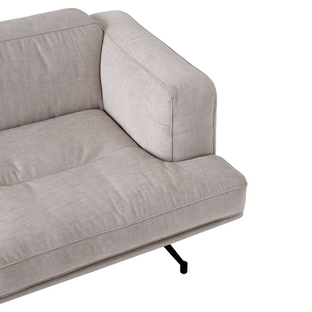 Light beige fabric sofa with a smooth texture and minimalist design, featuring subtle tufted patterns and black metal legs.