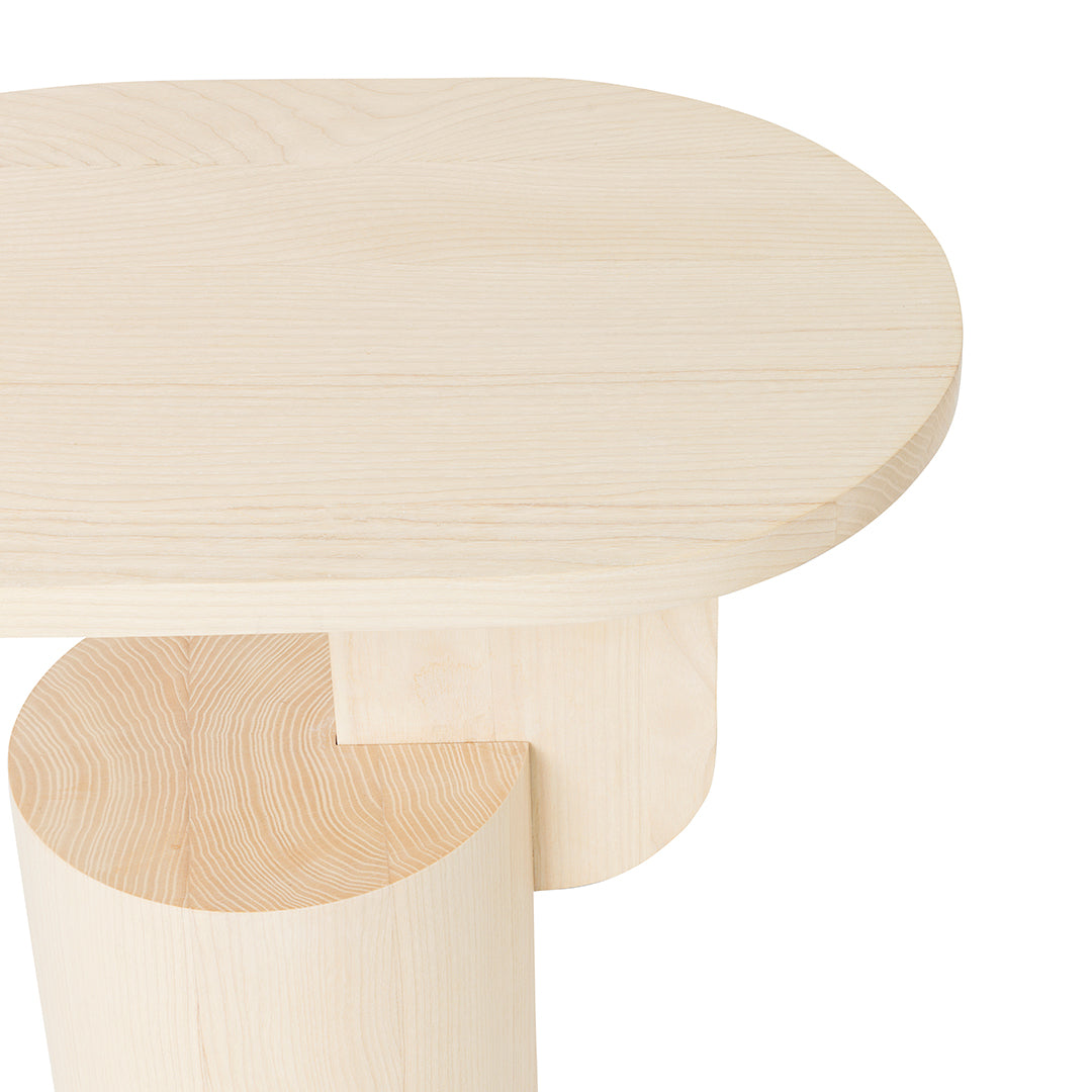 Natural light wood table with a smooth, oval top and rounded base, showcasing a minimalist design and subtle grain patterns.