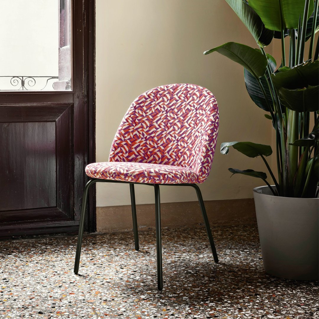 "Colorful patterned chair with pink, red, and white design on a sleek black metal base."