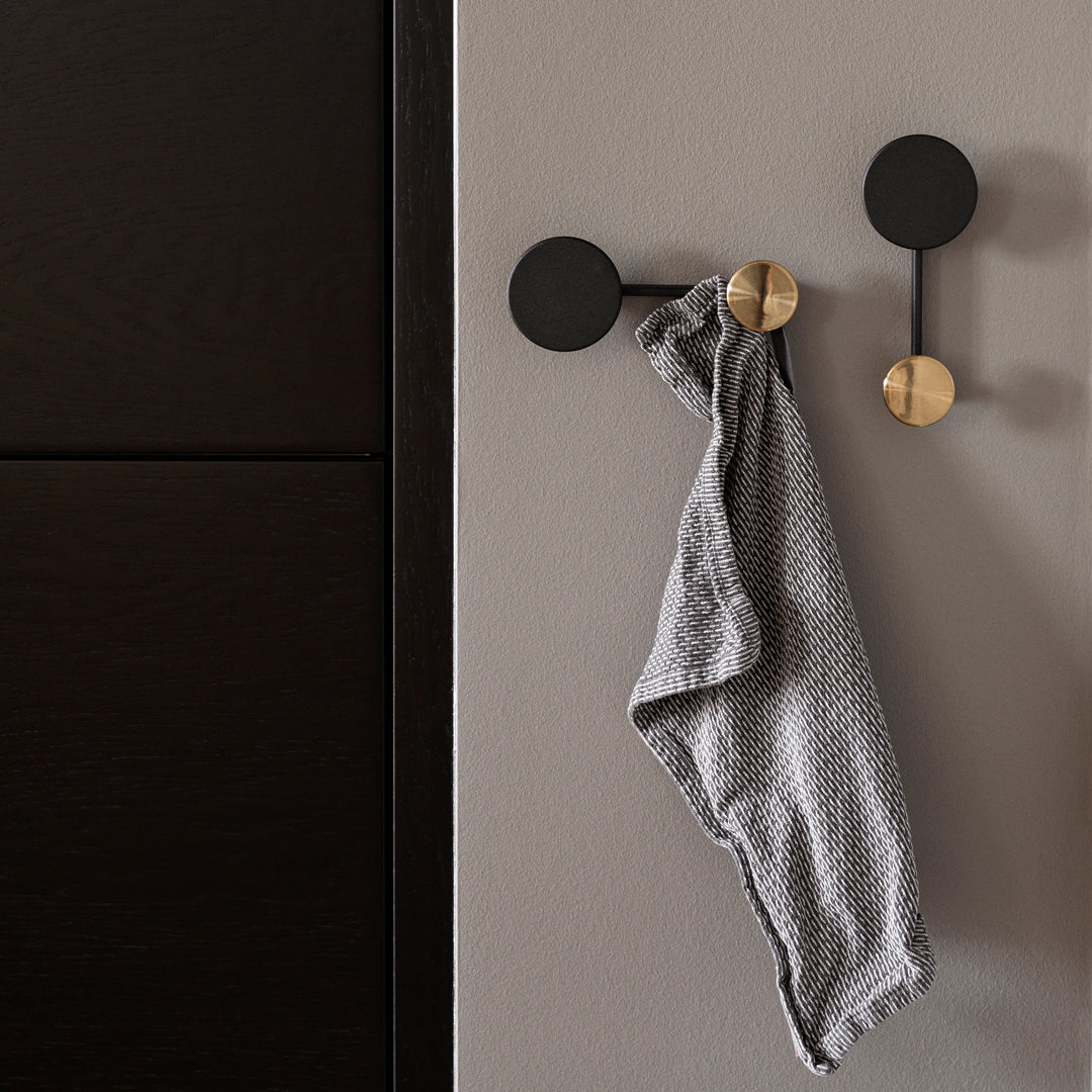 Stylish black wall hooks with a textured gray towel, featuring a modern gold accent. Perfect for contemporary decor.