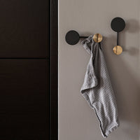 Stylish black wall hooks with a textured gray towel, featuring a modern gold accent. Perfect for contemporary decor.