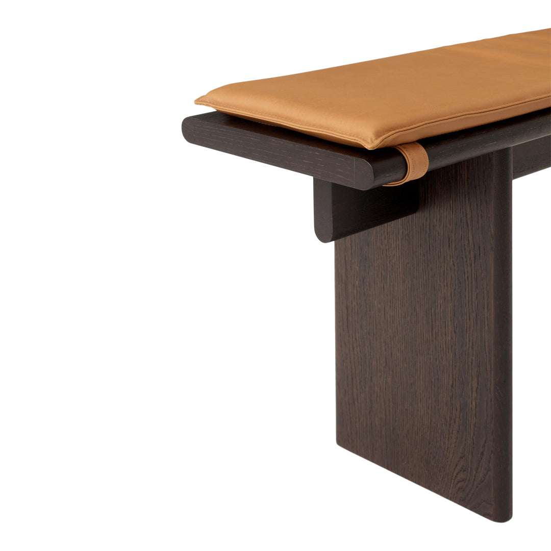 Brown leather cushion on a sleek dark wooden bench with clean lines and minimalistic design. Perfect for modern decor.