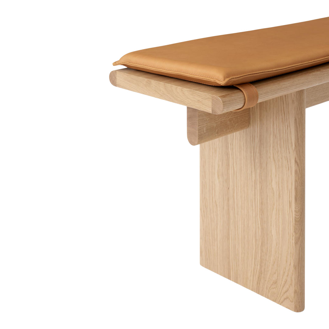 Light wood bench with a smooth oak finish and a rich tan leather cushion. Simple, modern design.