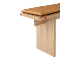 Light wood bench with a smooth oak finish and a rich tan leather cushion. Simple, modern design.