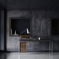 Sleek black desk with wooden accents against a dark textured wall, featuring gold-framed mirrors. Modern minimalistic design.